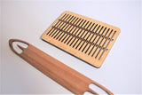Double-holed rigid heddle made of Baltic birch with hardwood shuttle for band weaving, side angle view